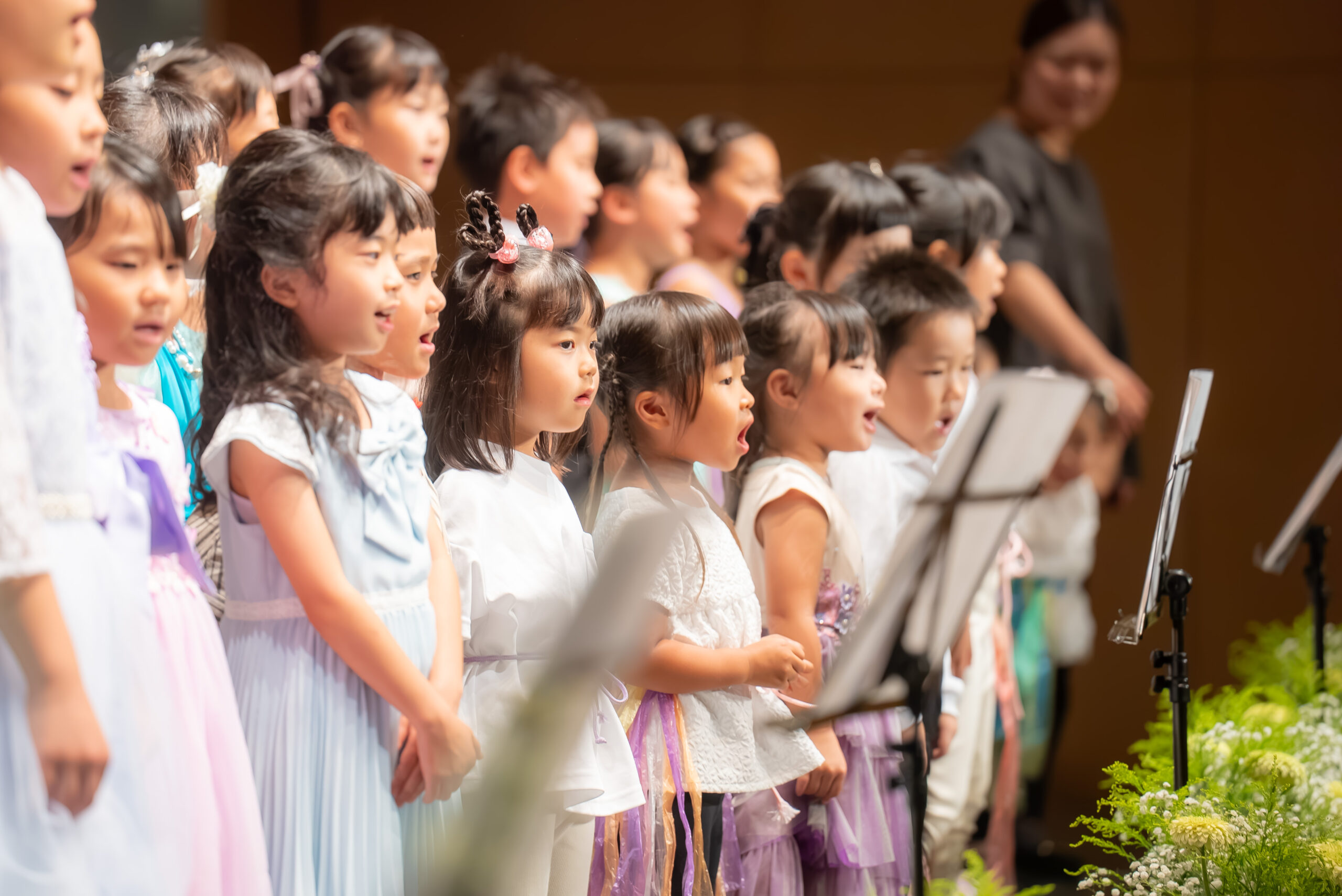 発表会の舞台で生徒と保護者へ語りかける関口あゆみ